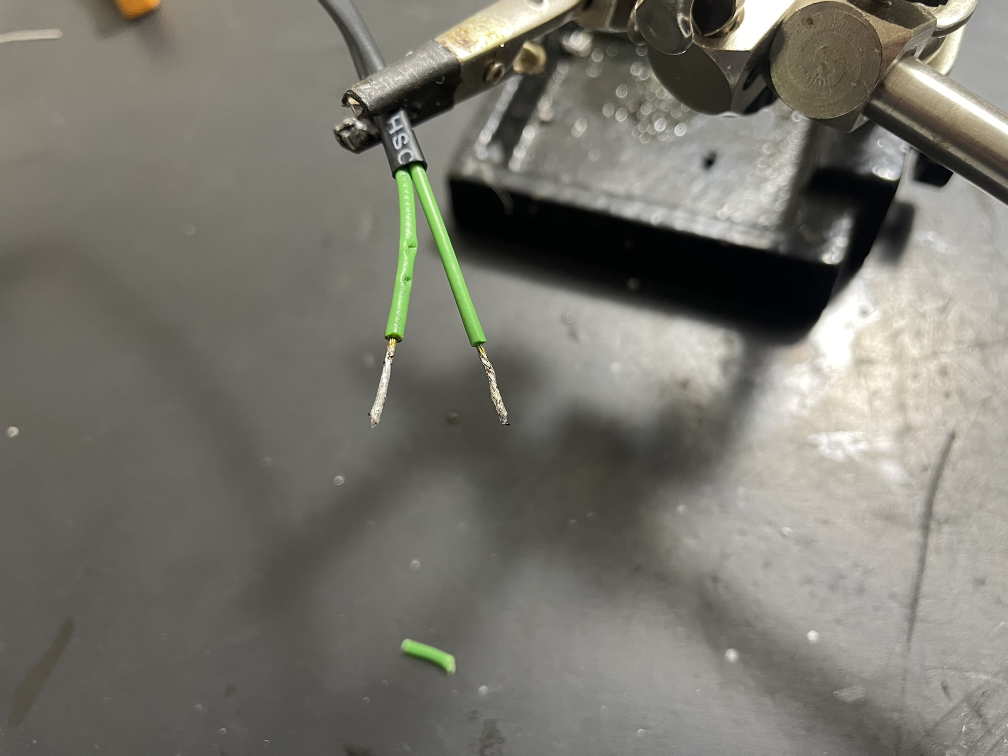 A small electronic component with green wires connected to it on a workbench.
