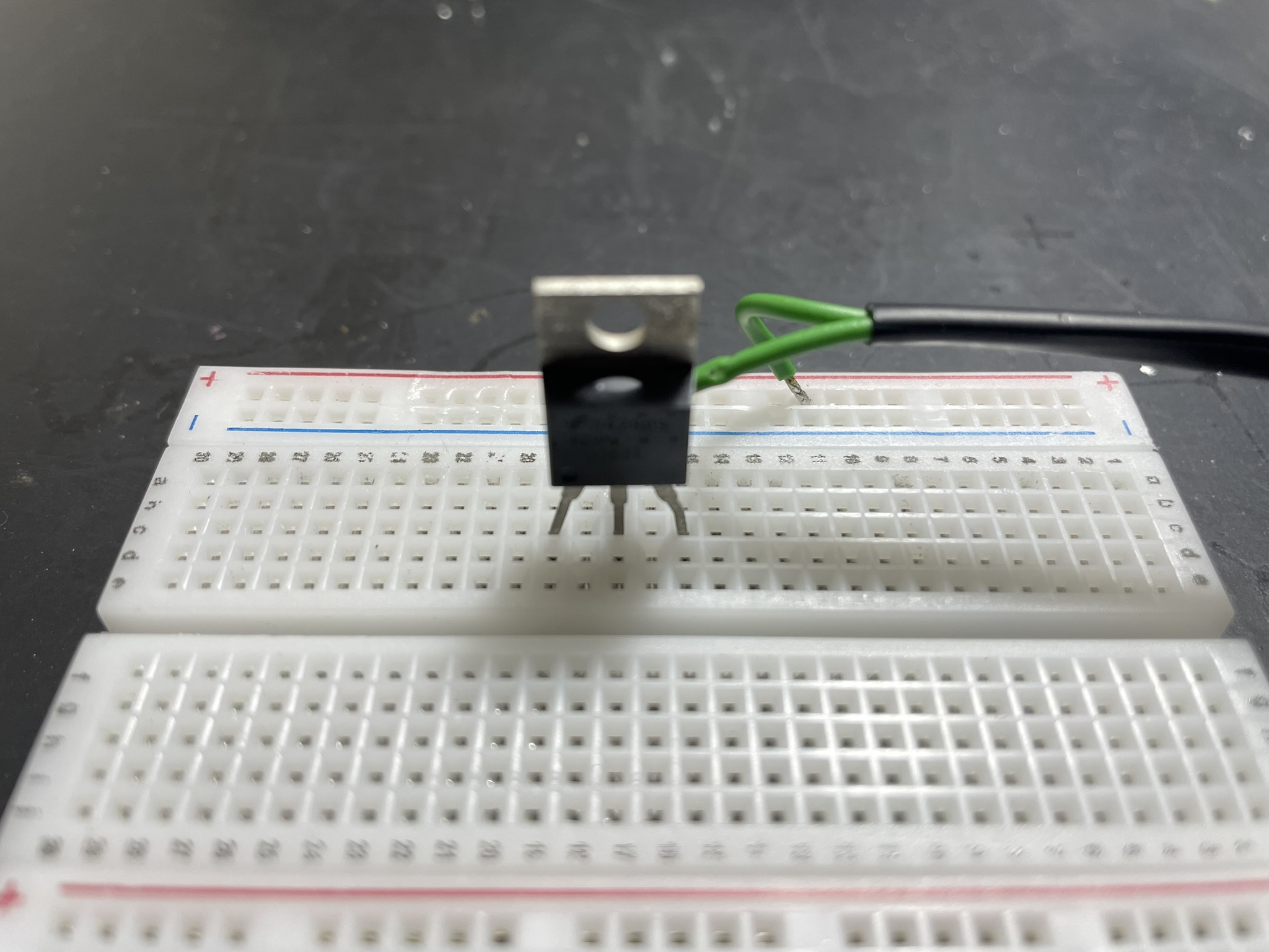 A MOSFET is soldered to a breadboard, connected to a microcontroller and various electronic components.