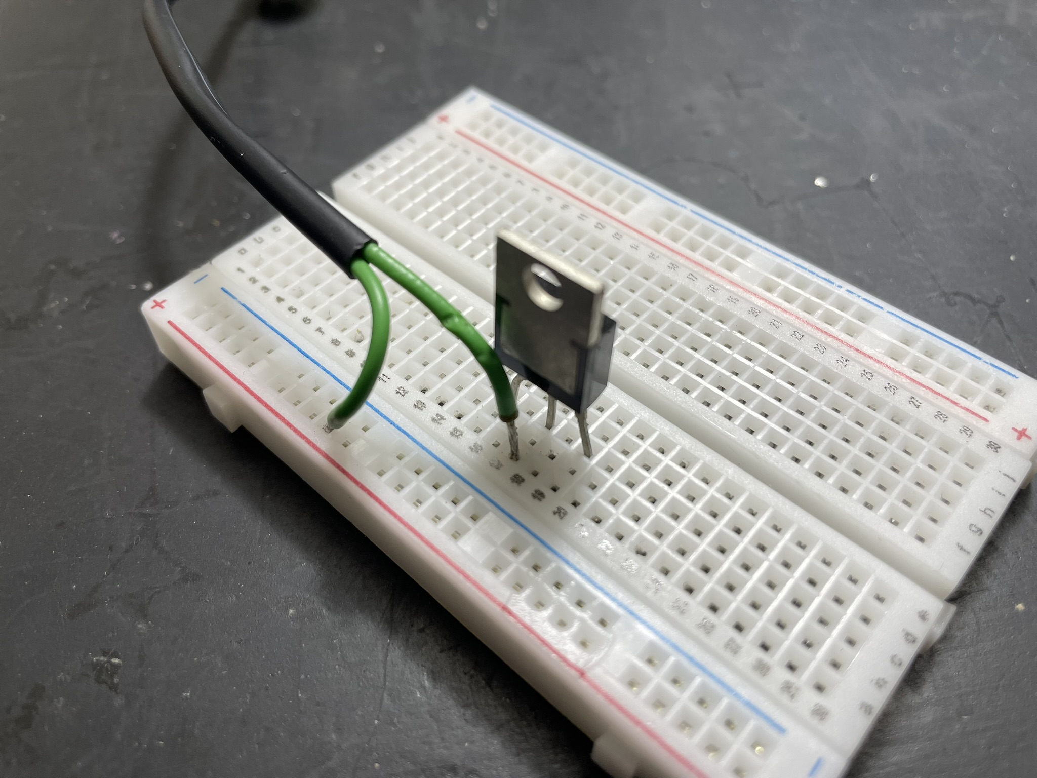 A breadboard setup with an IC socket and jumper wires, featuring a MOSFET component.