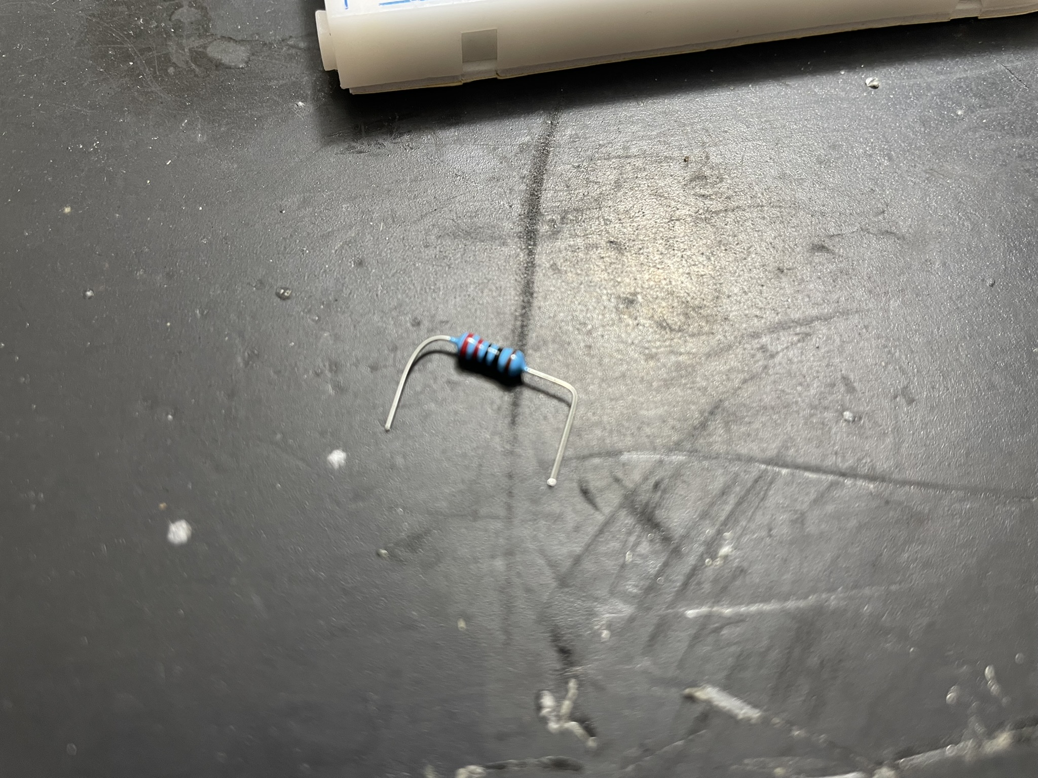 A cylindrical capacitor with a metal base and blue-red striped clip is shown, indicating polarity.