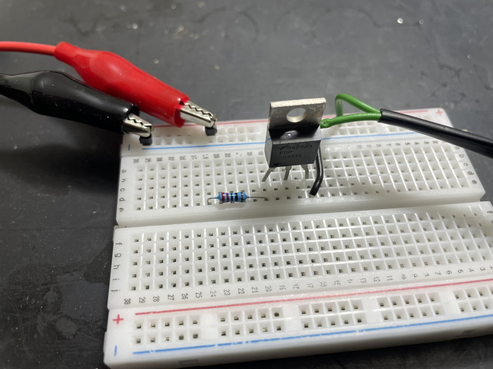An electronic breadboard with various components, including a resistor, LEDs, capacitor, IC chip, and power source,