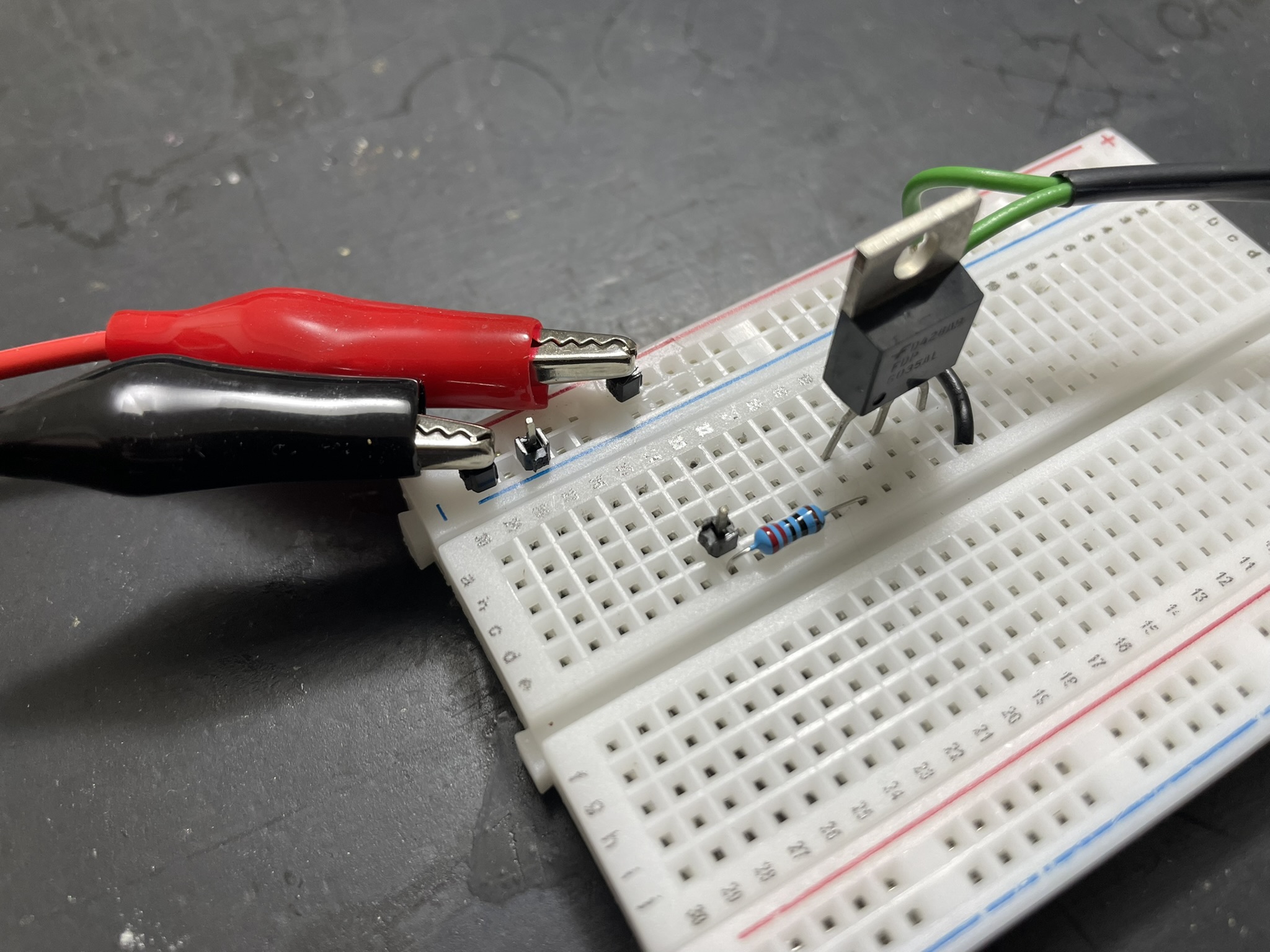 A breadboard circuit with a 220 Ohm resistor connecting logic signal provider to MOSFET gate.