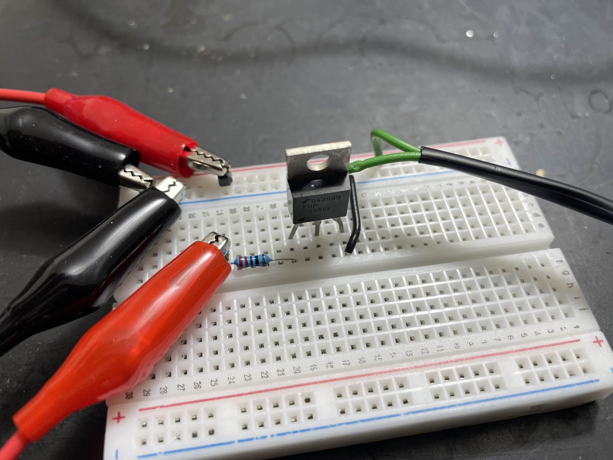 A breadboard with lit LED, microcontroller, and power sources for prototyping electronic circuits.