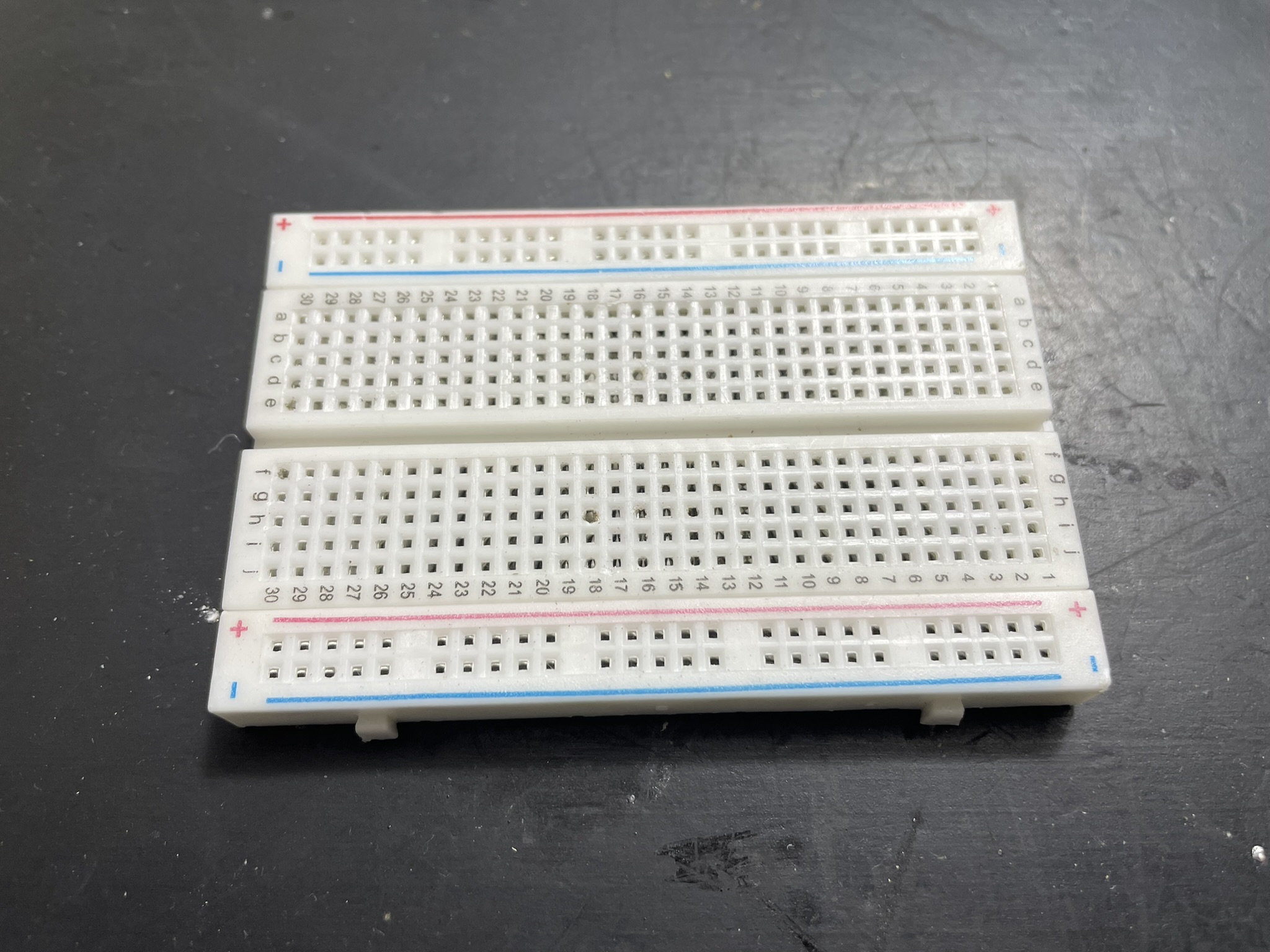 Two white electronics prototyping breadboards sit on a flat surface, appearing clean and undamaged.