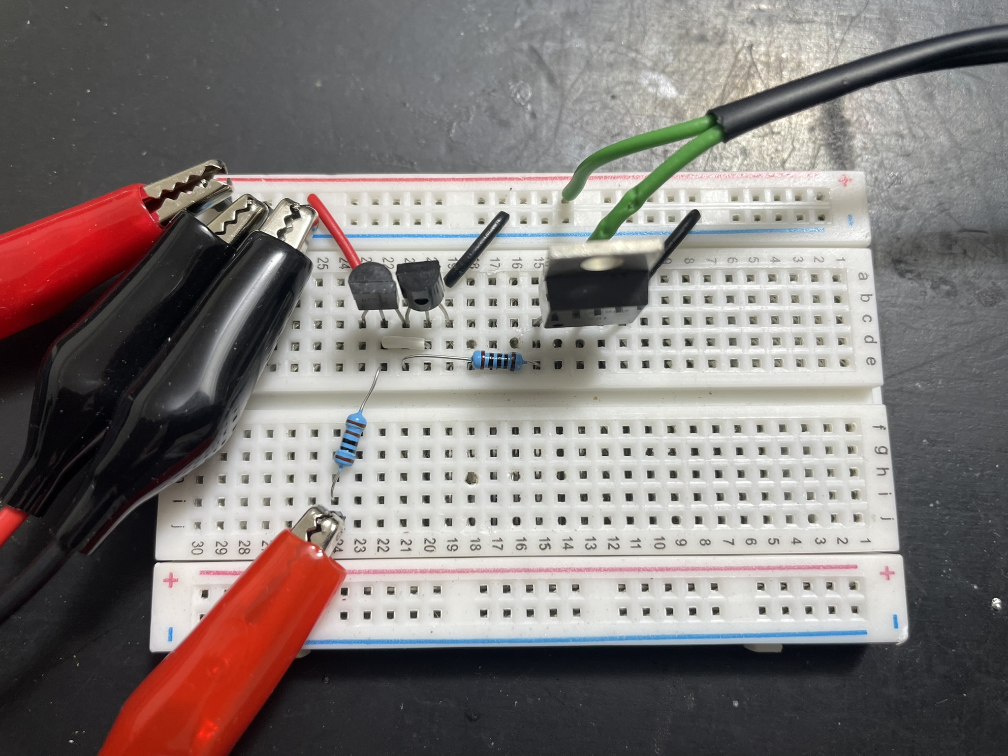 A breadboard with electronic components, jumper wires, and multimeters for testing a circuit.
