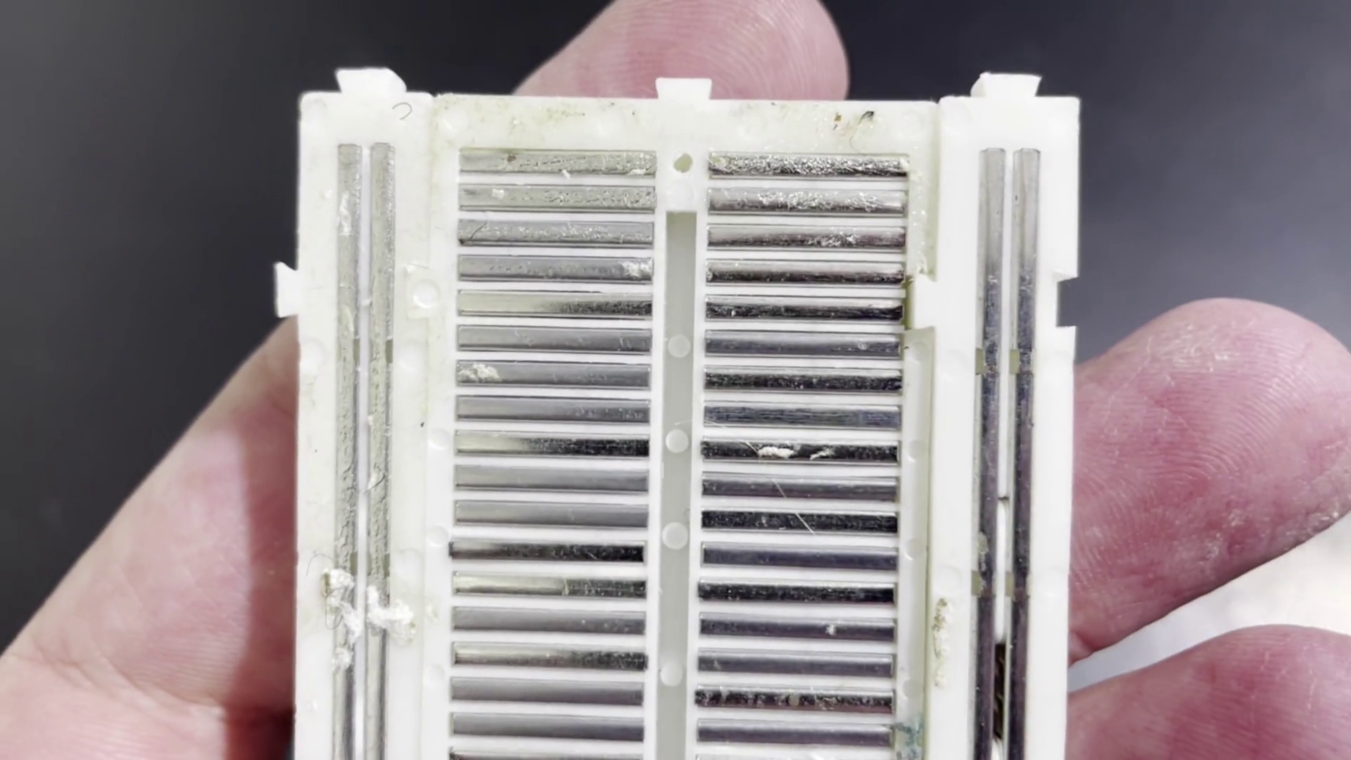 Backside of a classic plastic breadboard for prototyping, shows how pins are connected with metal strips.