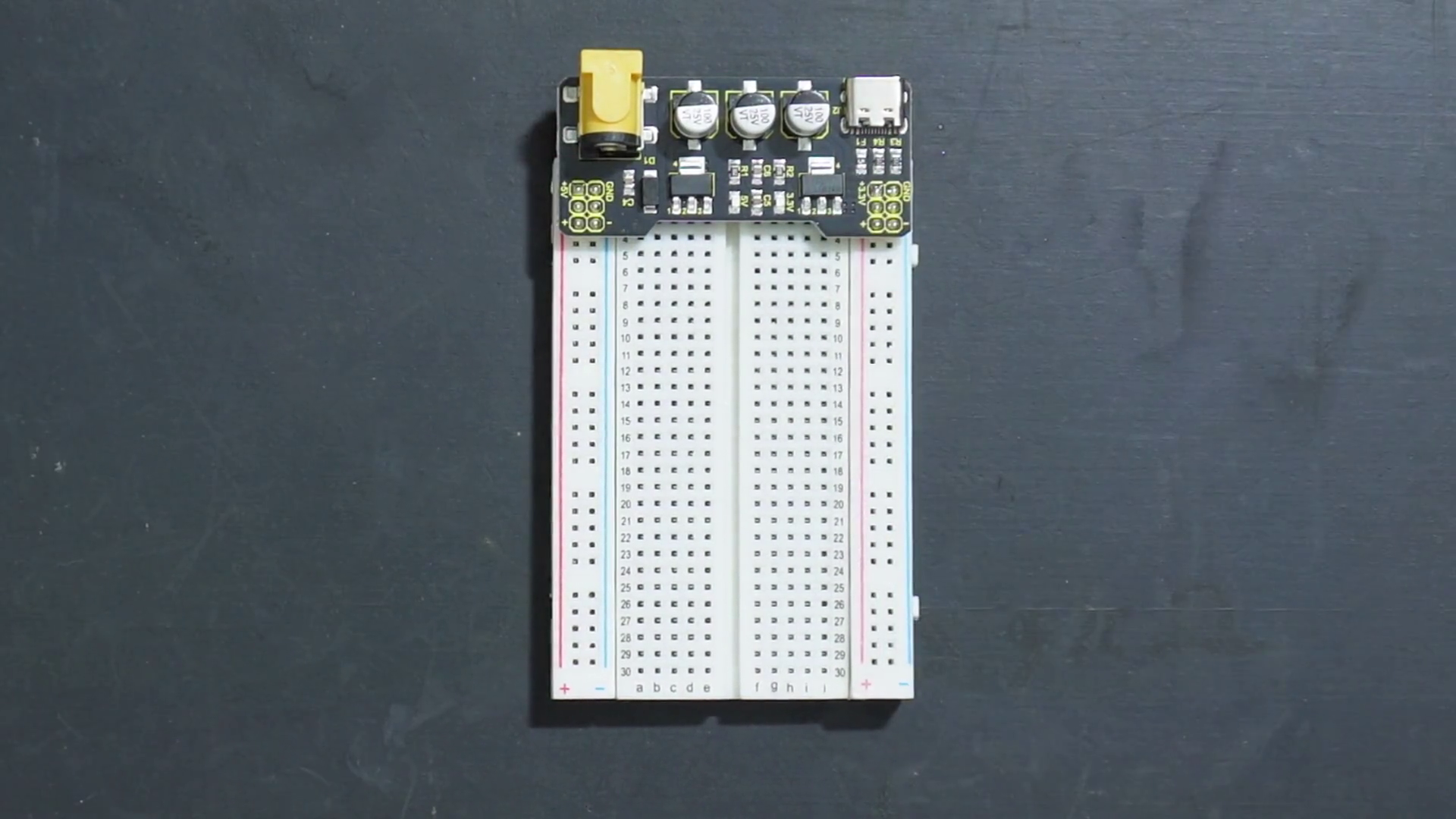 Breadboard power supply module with 12V input from barrel jack or USB-C charger, providing 5V and GND to long rails