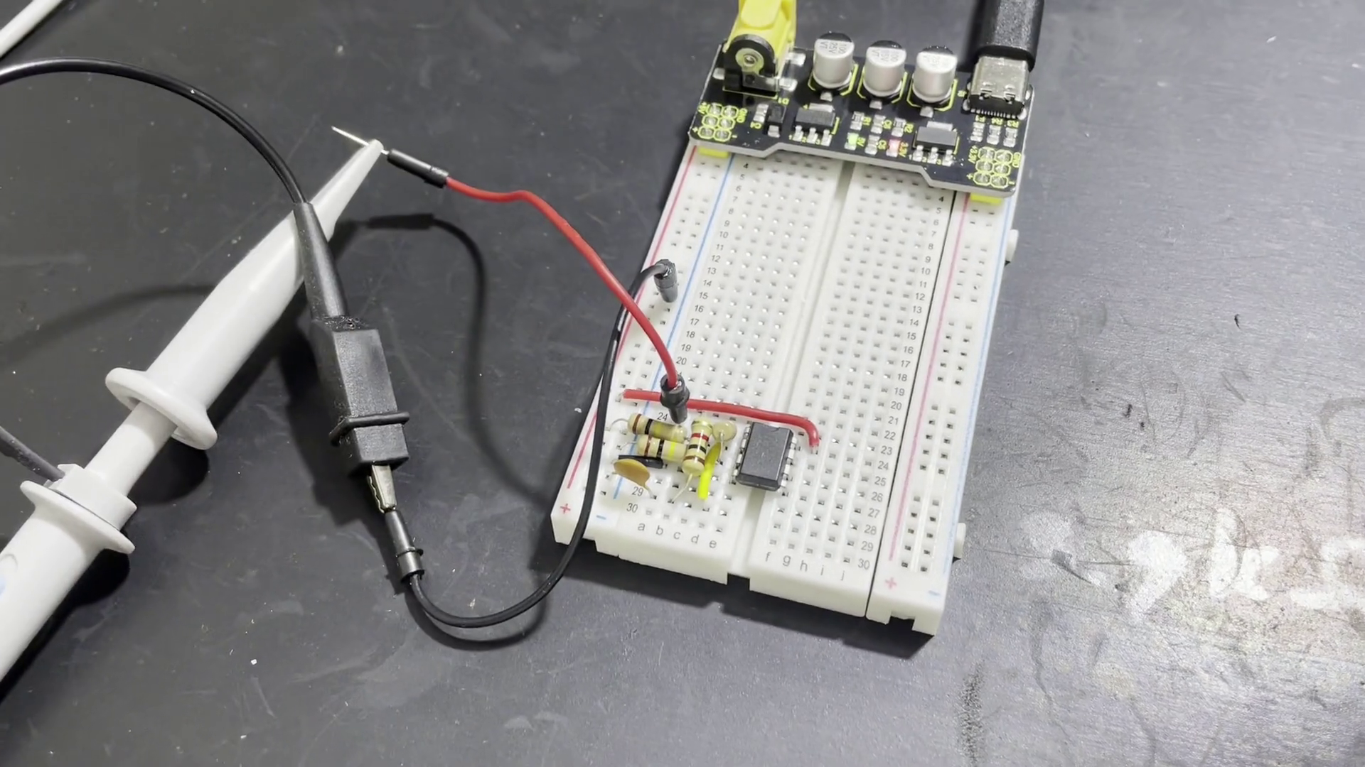 Oscilloscope probes connected to and oscillator circuit on a breadboard.